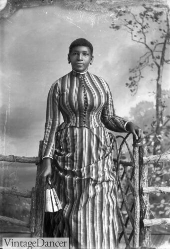 1890s black woman striped dress holding a hand fan
