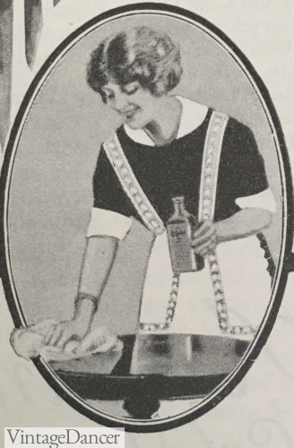 1928 black dress, white cuffs and collar and a white half apron with shoulder straps