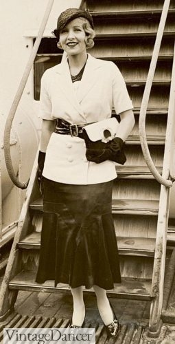  1930s fashion for women 1932 outfit with dark skirt, white jacket, wide belt, clutch purse