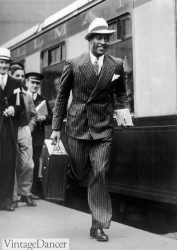 1940s black man wearing Double breasted stripe suit and ivory fedora to the train station carring luggage