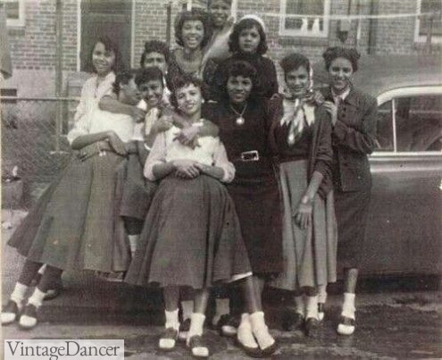 1950s teen girls wearing poodle skirts, blouses and saddle shoes
