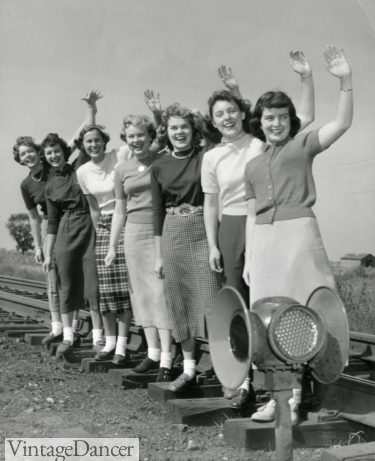 1950s teen girls wearing midi length skirts and sweaters with bobby socks and flat shoes
