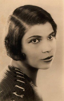 1920s black makeup daytime Charlotte E Ray wears a deep red lipstick, lined eye, arched eyebrows, and possibly light shadow