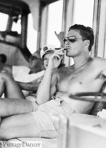 1940s mens sunglasses. Errol Flynn wearing thick plastic rim aviator glasses with dark lenses.
