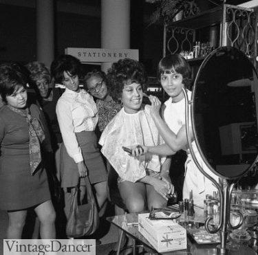 Flori Roberts Cosmetics makeup artist demonstrating products to women, Los Angeles, 1970
