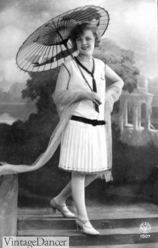 1920s a girl wears a summer white dress with blue sailor necktie nautical theme with paper parasol